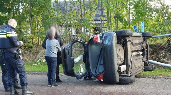 Auto op de kant na botsing met lantaarnpaal