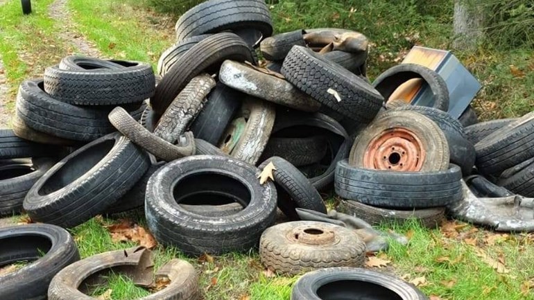 Grote bult met tientallen autobanden gedumpt midden in het bos